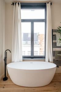 een groot wit bad voor een raam bij Gezellig gerenoveerd herenhuis in het centrum in Antwerpen