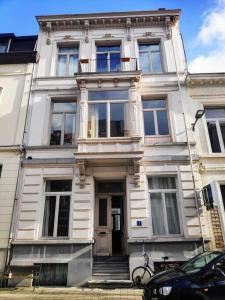 een wit gebouw met een deur en een auto voor de deur bij Gezellig gerenoveerd herenhuis in het centrum in Antwerpen