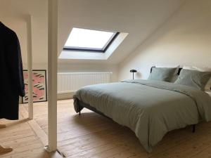 een slaapkamer met een groot bed en een dakraam bij Gezellig gerenoveerd herenhuis in het centrum in Antwerpen