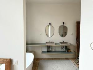 een badkamer met een wastafel en 2 spiegels bij Gezellig gerenoveerd herenhuis in het centrum in Antwerpen