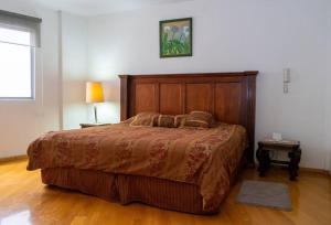 a bedroom with a large bed with a wooden headboard at Colonial Charm. Experience historic Quito. in Quito