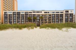 a building on the beach next to a sandy beach at Peppertree by the Sea by Capital Vacations in Myrtle Beach