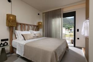 a bedroom with a large bed and a balcony at Ammothines Beach Suites in Chrysi Ammoudia