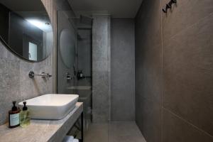 uma casa de banho com um lavatório branco e um espelho. em Ammothines Beach Suites em Chrysi Ammoudia