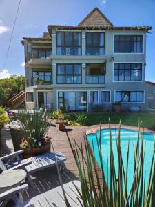 a large house with a swimming pool in front of it at Sola Fide Self Catering Apartment in Jeffreys Bay