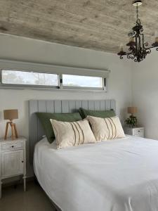 Un dormitorio con una gran cama blanca y una ventana en Pinar del Oriental, en José Ignacio