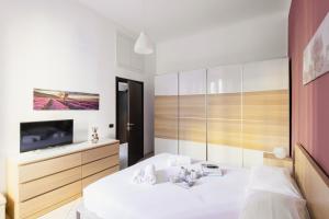 een slaapkamer met een wit bed en een televisie bij Easylife - Oasi di comfort 5 min da Centrale in Milaan