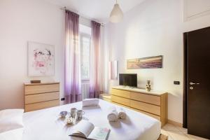 een slaapkamer met een wit bed en een televisie bij Easylife - Oasi di comfort 5 min da Centrale in Milaan