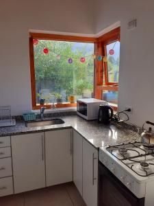 a kitchen with a sink and a microwave and a window at La casa de arriba in El Bolsón +6 photos