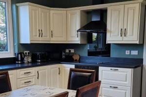 a kitchen with white cabinets and a table in it at Westland Retreat - Magherafelt - Mid Ulster - NITB Approved in Magherafelt