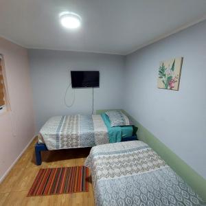 a bedroom with two beds and a flat screen tv at Hospedaje Walgün in La Serena