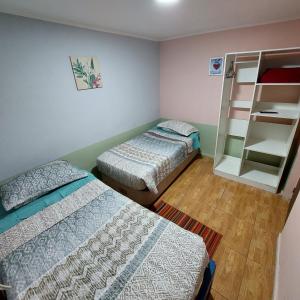 Habitación con 2 camas y estante para libros en Hospedaje Walgün en La Serena