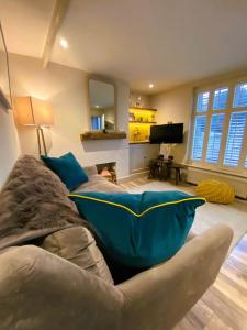 a living room with a couch with a blue pillow at Luxury Coastal Cottage with free parking - 5 mins walk to town & beach in Aldeburgh