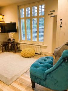 a living room with a blue couch and a television at Luxury Coastal Cottage with free parking - 5 mins walk to town & beach in Aldeburgh