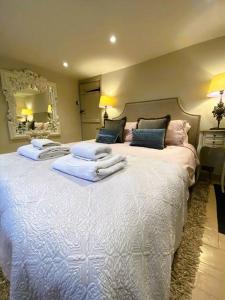 1 dormitorio con 1 cama blanca grande y toallas. en Stunning Coastal Cottage with free parking - easy stroll to town & beach, en Aldeburgh