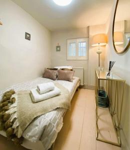 sypialnia z łóżkiem, stołem i lustrem w obiekcie Stunning Coastal Cottage with free parking - easy stroll to town & beach w mieście Aldeburgh