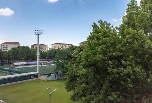a tennis court in a park with trees and buildings at Trilocale immerso nel verde in Turin