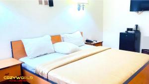 - une chambre avec un lit doté de draps et d'oreillers blancs dans l'établissement Cozyworld Hotel, à Ikeja