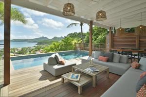 een woonkamer met een bank, een tafel en een zwembad bij Villa Nagabaaja in Saint Barthelemy