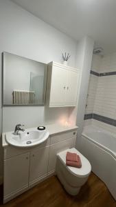 a bathroom with a sink and a toilet and a tub at Cosy Corner in Midhurst