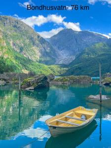 a boat sitting in the water with mountains in the background at Apartment-B near Etne-Odda in Etnesjøen