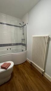 a bathroom with a tub and a toilet and a radiator at Cosy Corner in Midhurst