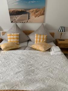 a bed with pillows and a picture of a beach at Haus Valentina in Archsum