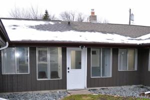 een huis met een witte deur en sneeuw op het dak bij Studio 7 in Grand Forks