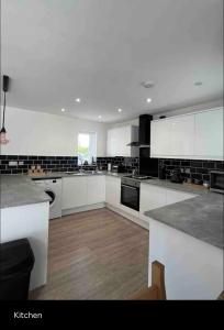 cocina grande con armarios blancos y electrodomésticos negros en Green 3 bed bungalow with en-suite and parking, en Felton