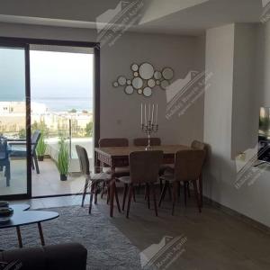 een eetkamer met een tafel en stoelen en een balkon bij Duplex 3 bedroom ocean view Taghazout Bay Tamourit in Taghazout