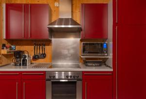 a kitchen with red cabinets and a stove top oven at My Chalet In Murau in Sankt Georgen ob Murau