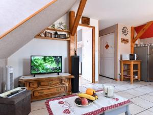 ein Wohnzimmer mit einem TV und einem Tisch mit Obst in der Unterkunft Gîte charmant au calme, 2 personnes, proche vignobles et châteaux, animaux acceptés, terrasse jardin - FR-1-744-33 in Bergheim