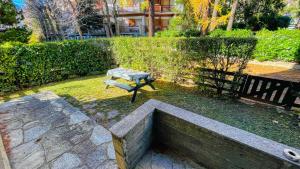 a bench and a table in a yard with a hedge at Appartamento Einaudi 11 - Affitti Brevi Italia in Bardonecchia
