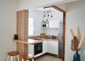 - une petite cuisine avec des placards blancs et un comptoir dans l'établissement Appartemment T2 cosy et spacieux : l’Oasis urbaine, à Les Abymes