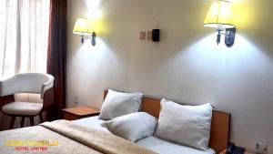 ein Hotelzimmer mit einem Bett mit weißen Kissen in der Unterkunft Cozyworld Hotel in Ikeja