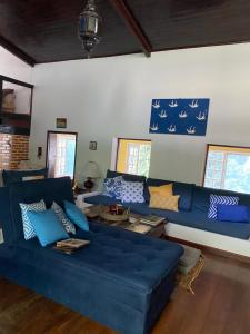 uma sala de estar com sofás azuis e janelas em Pousada Casa da Montanha em Angra dos Reis