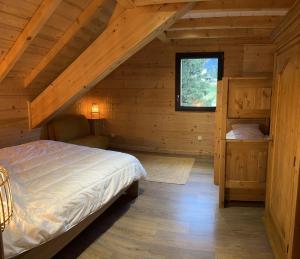 ein Schlafzimmer in einem Blockhaus mit einem Bett und einem Fenster in der Unterkunft Chalet La Morte in La Morte