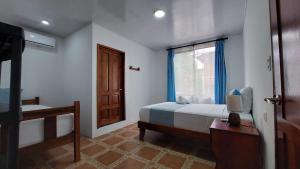 a bedroom with a bed and a window and a desk at Casa THIREMA Tortuguero in Tortuguero