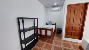 Habitación pequeña con cama y puerta de madera en Casa THIREMA Tortuguero en Tortuguero