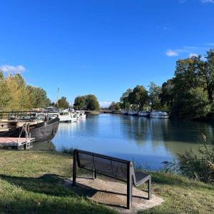 um banco sentado ao lado de um rio com barcos em Les Logis du Port - Port Canal - Montauban em Montauban