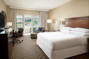 Habitación de hotel con cama blanca grande y escritorio. en Sheraton Sonoma Wine Country Petaluma en Petaluma