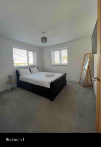 a bedroom with a large bed with two windows at White 3 bed bungalow with en-suite and parking in Winford