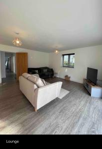 a living room with a couch and a television at White 3 bed bungalow with en-suite and parking in Winford