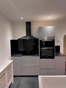 a kitchen with white cabinets and a stove top oven at Luxury 3 bedroom house -Private parking, sleeps 6, & featuring en-suite master bedroom in Birmingham