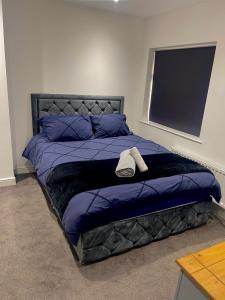a bed with a purple comforter and a hat on it at Luxury 3 bedroom house -Private parking, sleeps 6, & featuring en-suite master bedroom in Birmingham