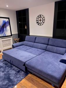 a blue couch in a living room with a clock on the wall at Luxury 3 bedroom house -Private parking, sleeps 6, & featuring en-suite master bedroom in Birmingham