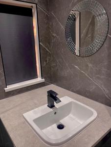 a white sink in a bathroom with a mirror at Luxury 3 bedroom house -Private parking, sleeps 6, & featuring en-suite master bedroom in Birmingham