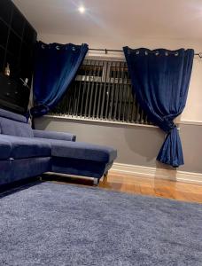 a living room with a blue couch and blue curtains at Luxury 3 bedroom house -Private parking, sleeps 6, & featuring en-suite master bedroom in Birmingham