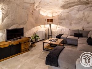 a living room with a large stone wall at Gîte troglodyte unique avec jacuzzi, billard et jardin, près de Doué La Fontaine et Saumur - FR-1-622-69 in Les Ulmes