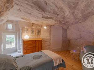 a bedroom with a bed and a stone wall at Gîte troglodyte unique avec jacuzzi, billard et jardin, près de Doué La Fontaine et Saumur - FR-1-622-69 in Les Ulmes